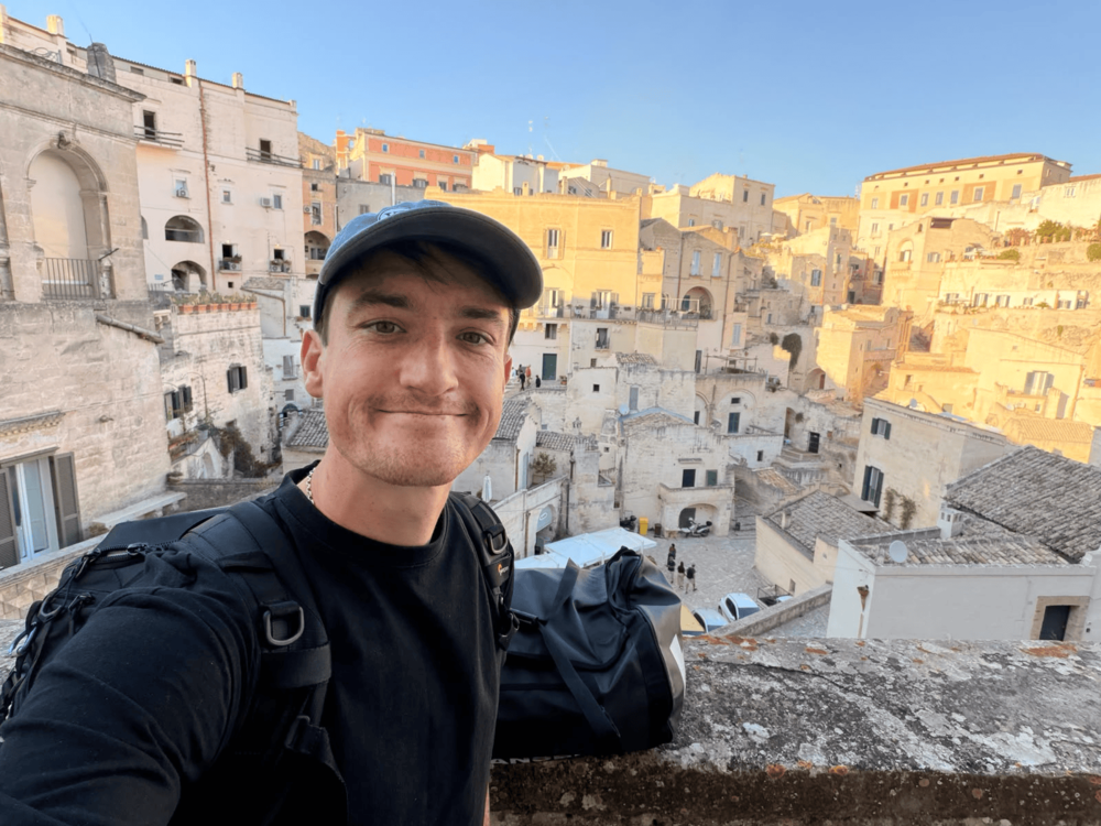 Cam with travel bags overlooking historic stone buildings