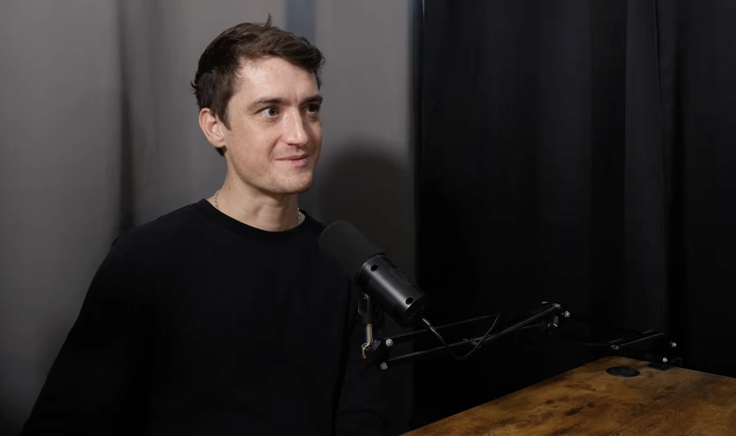 Cam seated at a podcast microphone